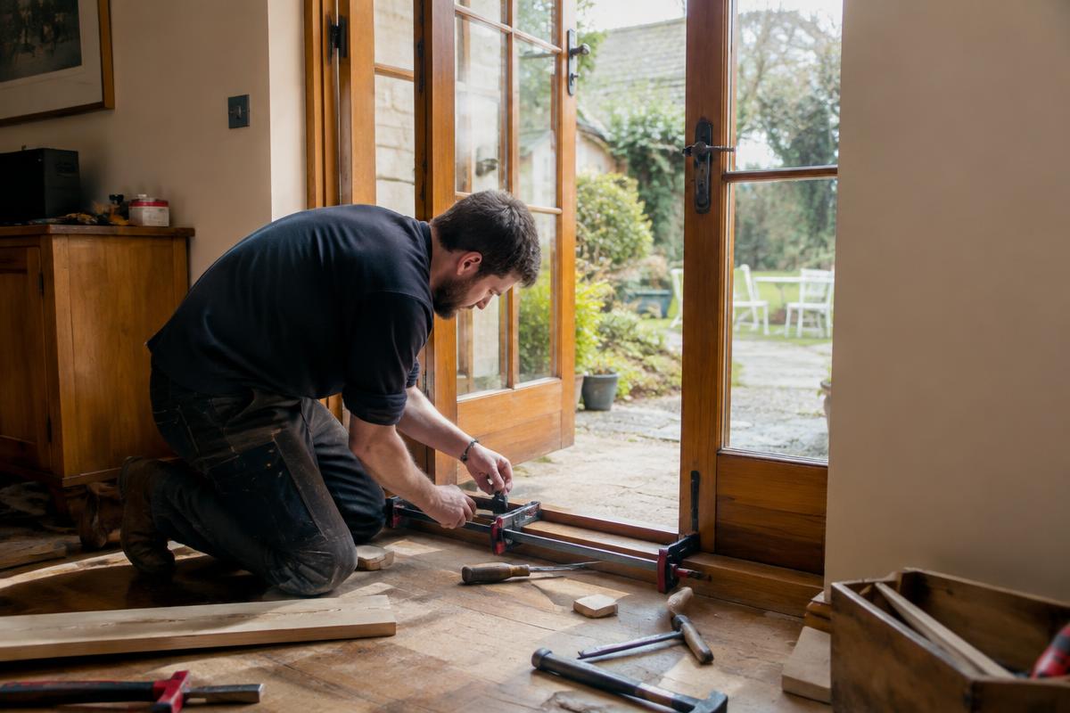Carpenter splicing new hardwood into the bottom rail of a timber French door